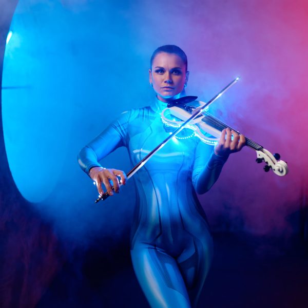 Beautiful violinist wearing tight tracksuit playing classic music in neon light. Futuristic, sci-fi loft design